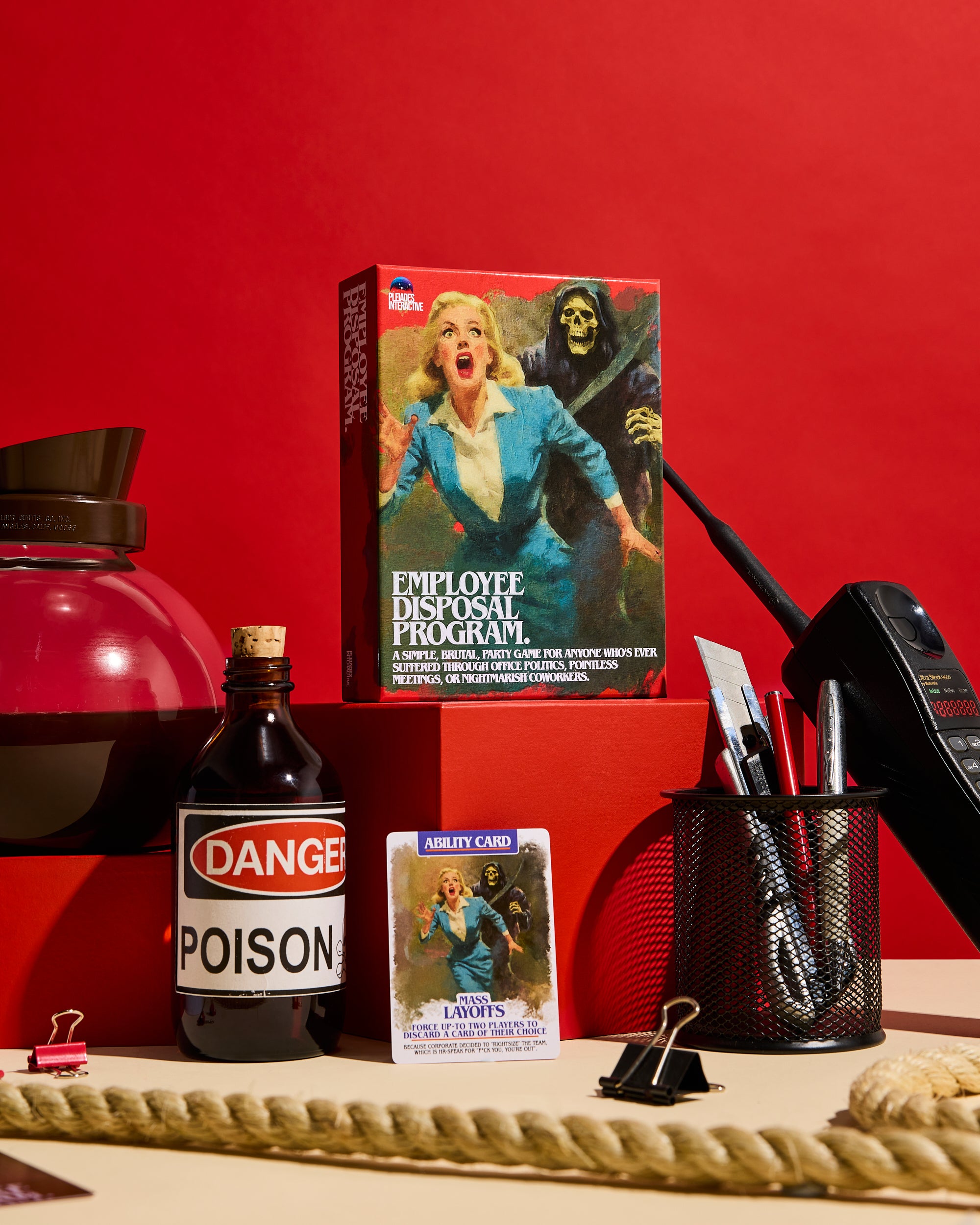 Employee Disposal Program Deluxe box on a red plinth with Mass Layoffs card and vintage office props